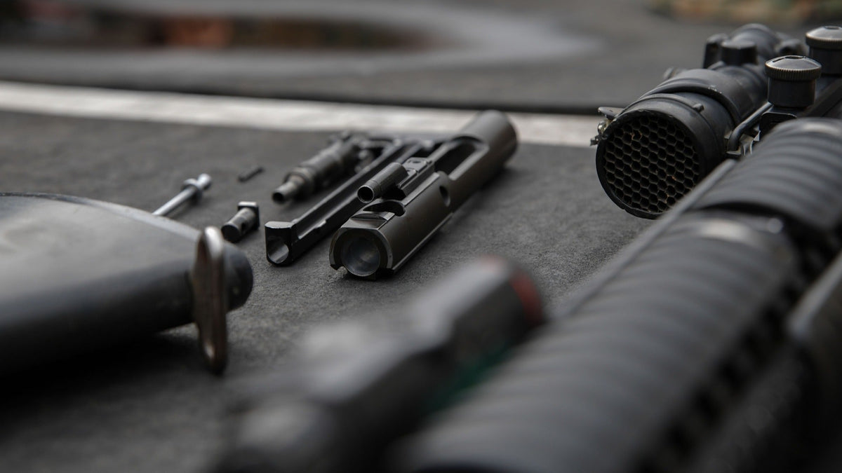 Disassembled rifle components arranged on a workbench during routine firearm cleaning.