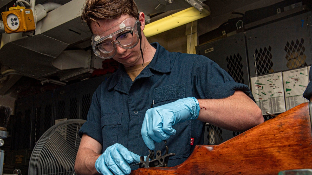 U.S. Navy gunner’s mate servicing internal components of an M14 rifle during firearm maintenance.